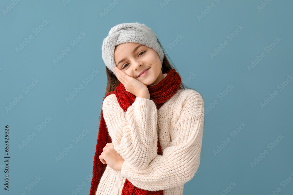Cute little girl in winter clothes on blue background