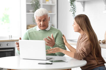 Canvas Print - Senior man with his granddaughter using laptop in kitchen