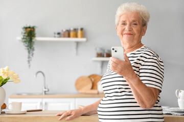 Sticker - Senior woman using mobile phone in kitchen