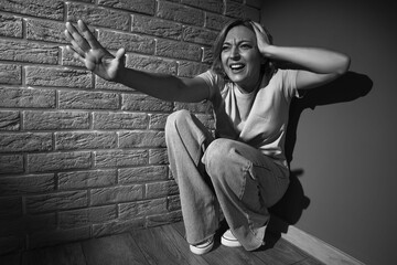 Scared mature woman sitting in corner