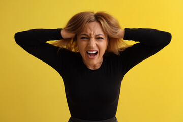 Poster - Scared mature woman screaming on yellow background