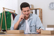 © New Africa - Seller talking on phone while working in office. Online store