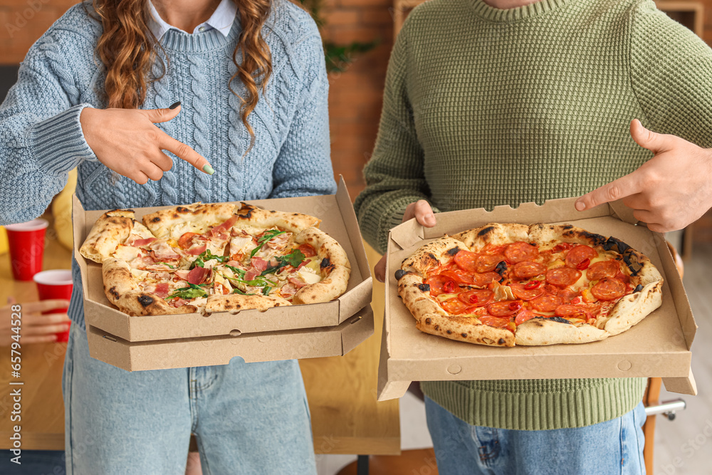 Young colleagues with tasty pizza at office party, closeup