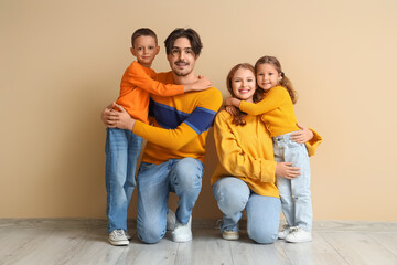 Poster - Happy family in warm sweaters hugging near beige wall