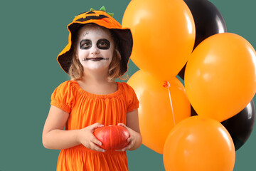 Wall Mural - Little girl dressed for Halloween with pumpkin and balloons on green background