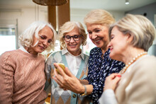 Senior group of female friends using a smartphone together at home