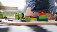 A little girl is playing a wooden construction set on a carpet in an open space. Educational games.