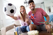 © NDABCREATIVITY - Young couple sport fans watching match on television at home