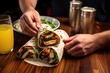 hand wrapping grilled veggies in a tortilla, pilsner beer on table