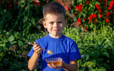 Wall Mural - boy eats honey in a flower garden. Selective focus.