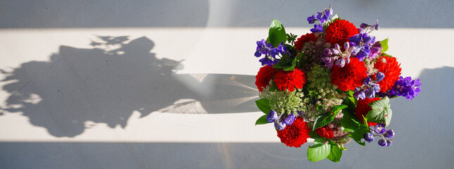 Sticker - view from above of a bouquet of flowers in a vase casting long shadows 