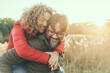 © simona - Young adult mature couple in love hugging and smiling with romance expression on face. One man carry woman in piggyback on his back. Female bonding male in outdoor leisure activity together. Happiness