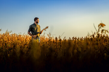 Wall Mural - Young farmer standing in a soy field examining crop before harvest.