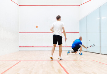 Wall Mural - Two young, concentrated and sportive men, friends playing squash together on squash court. Exercising and leisure. Concept of sport, hobby, healthy and active lifestyle, game, gym, ad