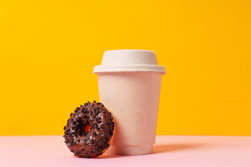 Wall Mural - Chocolate donut and paper cup on yellow background