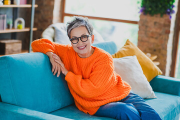 Wall Mural - Portrait of positive satisfied aged person sit cozy sofa toothy smile enjoy quite atmosphere modern house inside