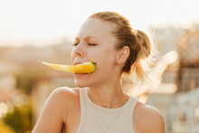 Woman Holding Piece Of Yellow Watermelon In Her Teeth