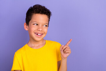 Wall Mural - Photo portrait of cute young schoolboy finger point look empty space wear yellow clothes isolated on purple color background