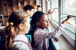 © Marko Geber - Young and diverse pupils looking out the window in a elementary school classroom