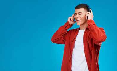 Aufkleber - Man, smile and headphones for song on break in studio by blue background. Asian person, listening and streaming the music, radio and audio or funny podcast in mockup, technology and sound for joy