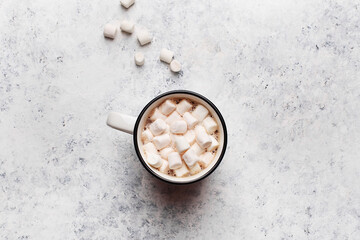 Mug with hot chocolate or cocoa with marshmallow on white concrete table. Overhead view, copy space. Winter background or greeting card. Hygge concept