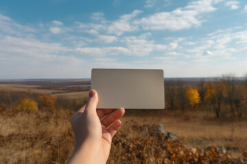 Poster - A person holding up a white card in a field. This versatile image can be used for a variety of purposes.