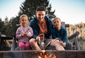 Wall Mural - Father roasting marshmallows with children enjoying outdoor family activity