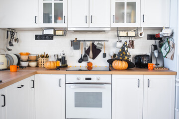 Decor of the white classic kitchen with pumpkins for Halloween and harvest. Autumn mood in the home interior, modern loft style.