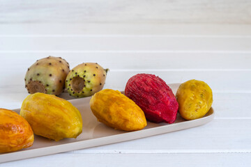 Wall Mural - Peeled Opuntia fruits (Prickly pears) on ceramic plate over wooden background.