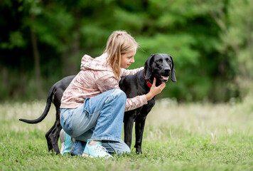 Sticker - Preteen girl hugging golden retriever dog sitting at nature together. Cute child kid petting purebred pet doggy labrador in park at summer