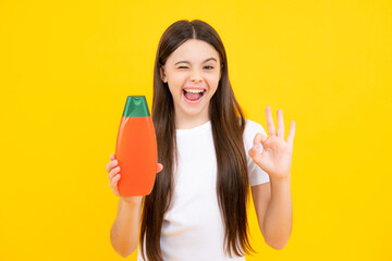 Poster - Teenager child girl showing bottle shampoo conditioners or shower gel. Hair cosmetic product. Bottle for advertising mock up copy space. Excited teenager, glad amazed and overjoyed emotions.