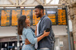 young family couple at the train station exited about oncoming travel in front of timetable