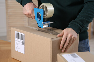 Canvas Print - Seller taping parcel at workplace in office, closeup. Online store