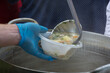 soup is poured into a plastic bowl with an iron ladle