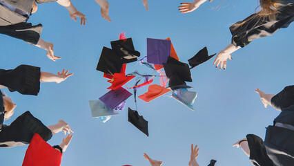 College graduates throw colorful hats up in the air.
