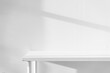 © Ratirath - Empty white desk with morning light and shadows of windows with copy space, summer concert. Blurred backdrop abstract background for display product.