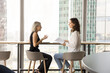 © fizkes - Positive mature businesswoman talking to young coworker girl, training intern, new employee. Busy younger and elder colleagues women discussing ideas for project, legal paper documents