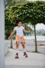 Happy teenage girl rollerblading in a skate park outdoors. A child plays on roller skates.