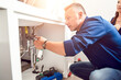 © Рика Тс - Plumber work with pipes under the sink and show owners where the problem is in the pipe under the sink