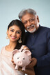 © Neha - indian father holding piggy bank with his daughter