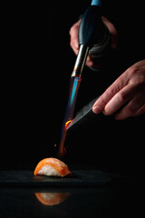 Wall Mural - Scorching, Flaming sushi with a torch.Roasting sushi with a burner on a dark background