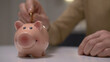 A man putting a coin in the piggy bank as part of budget planning and managing salary earnings for their pension fund