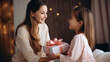 Happy mother receiving a gift from her daughter in living room - Mother's day concept
