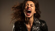 Portrait of a beautiful rocker woman in a black leather jacket on a studio background. Screaming girl isolted exemplifies youthful rebellion, alternative fashion, self-expression