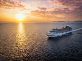 Wall Mural - panoramic aerial view of a cruise ship traveling over the ocean during golden summer sunset time