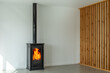 Fireplace inside house modern living room. Cosy living room with wood burner stove with burning flame behind a glass door