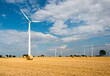 Windkraftanlagen auf einem abgeernteten Getreideacker  und Strohballen im Herbst
