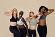 © insta_photos - Happy fit sporty diverse different girls group having fun posing at beige background. Multiracial positive young women friends wear sportswear advertising fitness gym yoga body trainings together.