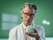 Älterer Mann mit medizinischem Beruf hält mit kritisch fragendem Blick ein Modell eines Gehirn vor sich