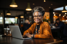 Mature Middle Aged African American Woman Using Laptop Working On Computer In Cafe. Businesswoman Distance Applicant, Aged Seeker Searching Job Online, Blogger Writer. Old People And Technology